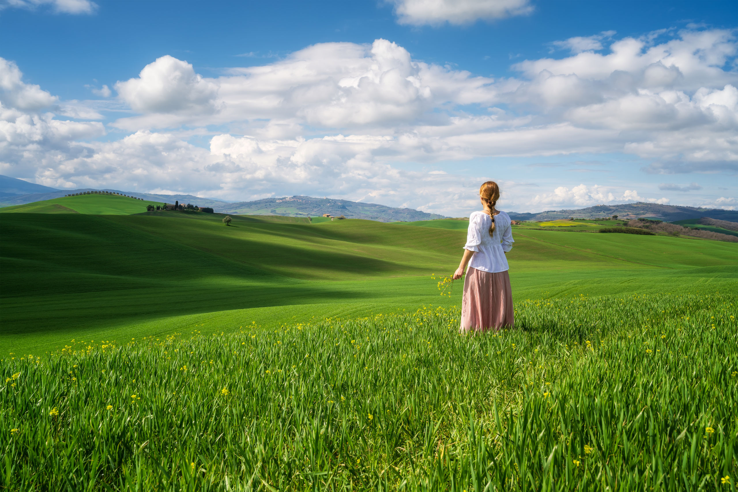 Woman stands in rolling Tuscany fields